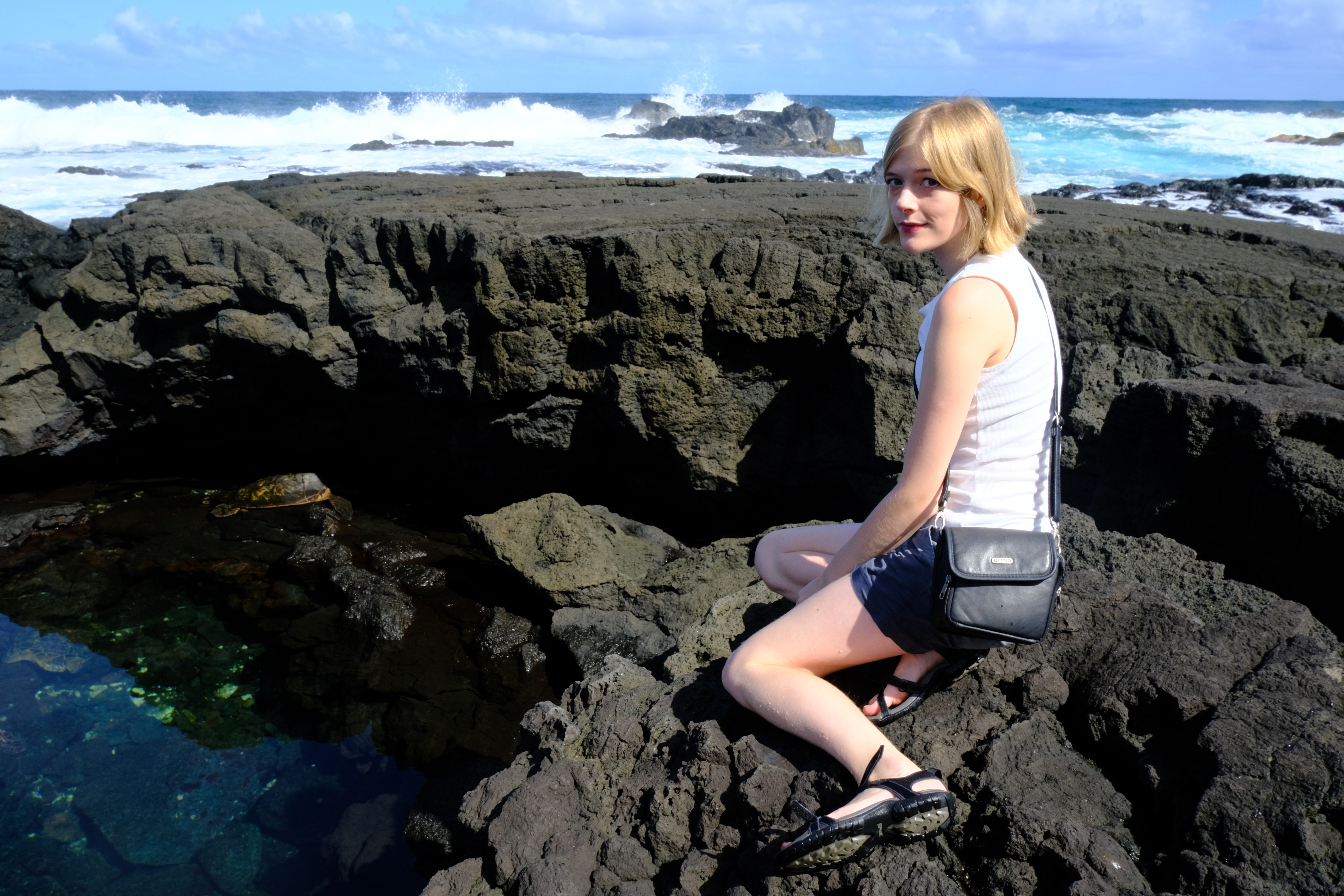 Grace sitting on rocks by the ocean.